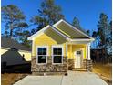 Beautiful yellow home with stone veneer, white trim, and a well-manicured lawn against a vibrant blue sky at 3135 Tiger Tail Rd., Conway, SC 29526