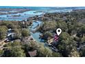 A scenic aerial view captures a lovely waterway home with a red roof amid a lush landscape and tranquil waters at 3615 Sunfish St., Murrells Inlet, SC 29576