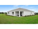 Back exterior of the house with a covered porch, chairs, and a lush green lawn at 8054 Bear Claw Ct., Conway, SC 29526