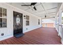 Spacious front porch featuring a stained wood floor, ceiling fans, and a decorative front door, perfect for relaxing at 8533 Cedar Trace Dr., Myrtle Beach, SC 29588