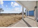 Covered front porch featuring white columns and brick accents, offering views of the surrounding landscape at 3372 Gurley Rd., Loris, SC 29569