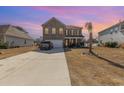 Two-story home with a spacious driveway, palm tree, and colorful sunset at 160 Ocean Commons Dr., Surfside Beach, SC 29575