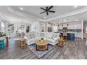 Open-concept living room with a ceiling fan, an area rug, hardwood floors, and a view into the kitchen at 3105 White Jasmine Dr., Little River, SC 29566