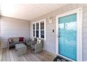 Cozy front porch featuring wicker seating, a glass-top table, and a vibrant blue door, creating an inviting entry at 311 51St Ave. N, North Myrtle Beach, SC 29582