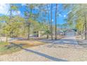 View of home, driveway, and detached garage through the trees and gravel entry at 87 Lake Trail, Pawleys Island, SC 29585