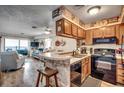 Open kitchen with wood cabinets, stainless steel appliances, and a breakfast bar overlooking the living area at 126 N Waccamaw Dr. # 203, Garden City Beach, SC 29576