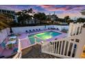A refreshing pool area with lounge chairs, tables, and a hot tub, surrounded by a privacy fence and lush greenery at 1420 S Ocean Blvd., North Myrtle Beach, SC 29582