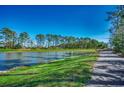 Peaceful pond view lined with green grass and tall trees, next to walking path under a blue sky at 1903 Francis Ct., Myrtle Beach, SC 29577