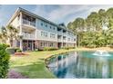 Corner view of the condo building overlooking a serene pond and lush green lawn at 5825 Catalina Dr. # 531, North Myrtle Beach, SC 29582