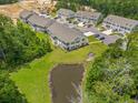 Aerial view of condos with a pond and lush trees surrounding the area showcasing the community layout at 933 Jackline Place # 101, Murrells Inlet, SC 29576