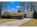 Inviting brick home featuring neat landscaping, a well-kept lawn, and a concrete driveway leading to an attached garage at 1917 Candy Ln., Surfside Beach, SC 29575
