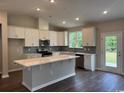 Bright kitchen featuring white cabinets, a spacious center island, stainless steel appliances, and views to the backyard at 453 Kapalua Loop, Little River, SC 29566