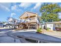 Charming two-story home on pilings featuring a welcoming porch and lush tropical landscaping at 6001-O32 S Kings Hwy., Myrtle Beach, SC 29575