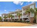Beautiful condo building with multiple units, bright white balconies, stairs, and surrounding palm trees at 6253 Catalina Dr. # 921, North Myrtle Beach, SC 29582