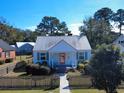 Charming cottage-style home with a metal roof, a picket fence, and a cozy front porch set against a clear blue sky at 632 Magnolia Dr., Georgetown, SC 29440