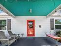 Inviting front porch featuring a bright red door, Adirondack chairs, and a comfortable bench at 632 Magnolia Dr., Georgetown, SC 29440