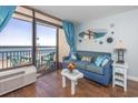 Relaxing living room with a blue sofa, sliding glass doors with ocean views, and bright decor at 6804 N Ocean Blvd. # 631, Myrtle Beach, SC 29572