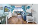 Cozy living room featuring a comfortable blue sofa, wood floors, and sliding glass doors to the balcony at 6804 N Ocean Blvd. # 631, Myrtle Beach, SC 29572