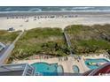 Aerial view of a beach with a pool area, green areas, and a walkway to the beach at 1401 S Ocean Blvd. S # 1003, North Myrtle Beach, SC 29582