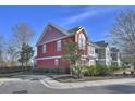 A two-story red townhome with a lush yard, shrubbery, and nearby street at 1654 Low Country Pl. # F End, Myrtle Beach, SC 29577