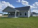 Back exterior view with a covered patio, windows, and large backyard at 242 Letha Dr, Longs, SC 29568