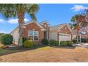 Brick home with side siding featuring manicured front bushes and a lawn with mature palm trees on a sunny day at 4517 Planters Row Way, Myrtle Beach, SC 29579