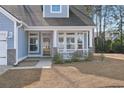 Close-up of the cozy front porch with white columns and railing of this charming light-blue house at 5501 Bristle Cone Ct., Myrtle Beach, SC 29577