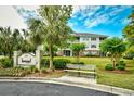 Well-manicured lawn with sign and park bench in front of condo building under blue skies at 5801 Oyster Catcher Dr. # 723, North Myrtle Beach, SC 29582