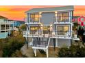 Rear exterior of elevated home with dual balconies, black railing, and staircase leading to the ground at 604 Ocean Boulevard W, Holden Beach, NC 28462