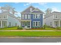 Inviting two-story blue home with well-kept lawn, accented by white trim and a cozy porch at 67 Bridgeview Rd., Georgetown, SC 29440