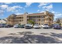 Three-story condo complex with ample parking, decks, and staircases viewed under a clear blue sky at 1025 Plantation Dr. W # 3412, Little River, SC 29566
