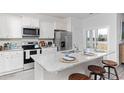 Modern kitchen boasts stainless steel appliances, white cabinetry, and a granite breakfast bar at 1451 Porchfield Dr., Conway, SC 29526