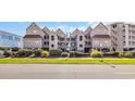 Exterior view of the condo complex featuring raised construction with a lush landscaped yard at 1113 N Ocean Blvd. # 101, Surfside Beach, SC 29575