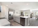Modern kitchen features stainless steel appliances, gray cabinets, a spacious island, and an adjacent dining area at 4517 East Coast Ln., Shallotte, NC 28470