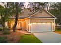 Beige home with white garage door, side patio with string lights, and manicured lawn at 9100 Sw Fountain St., Calabash, NC 28467