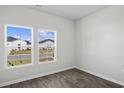 A bedroom featuring wood-look floors, neutral walls, and sunlit windows with views of neighborhood at 108 Saddle St, Conway, SC 29527
