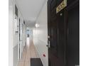 Condo hallway leading to a door with black door and neutral wall color and tile floors at 1210 N Waccamaw Dr. # 305, Murrells Inlet, SC 29576
