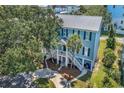 Aerial view of a charming raised beach home with metal roof, dual staircases, and landscaped surroundings at 1519 N Palmetto Dr., Surfside Beach, SC 29575