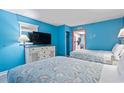 Bright bedroom with two beds, a dresser with a TV, and a view into the full kitchen at 201 S Ocean Blvd. # 217, Myrtle Beach, SC 29577