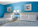 This cozy bedroom boasts beach-themed decor, two comfortable beds, and soft lighting at 201 S Ocean Blvd. # 217, Myrtle Beach, SC 29577