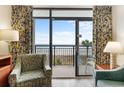 Cozy living room featuring comfortable armchairs, a lamp, and an ocean view through sliding glass doors to the balcony at 4800 S Ocean Blvd. # 204, North Myrtle Beach, SC 29582