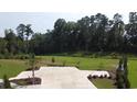 View of a parking lot and green space in the community surrounded by a heavily wooded area at 586 Honeyhill Loop, Conway, SC 29526