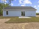 Rear exterior showcasing light blue siding and sliding glass doors opening to a concrete patio at 813 Highway 67, Loris, SC 29569