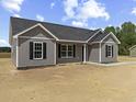 New home with gray siding, black shutters, and a concrete sidewalk and driveway on a sunny day at 825 Highway 67, Loris, SC 29569