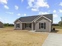 Charming new construction home featuring gray siding, black shutters, new sidewalk and driveway ready for its new owners at 825 Highway 67, Loris, SC 29569