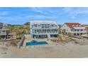 Beautiful blue beach house with a pool, spacious deck, white picket fence, and sandy beach access at 2201 S Waccamaw Dr., Murrells Inlet, SC 29576