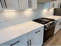 Modern kitchen features white cabinets, herringbone backsplash, and stainless steel gas range at 2317 Hazel Way, Longs, SC 29568