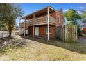 Back of red brick house with open wood balcony and fenced yard at 112 S Rosemary Ave., Andrews, SC 29510