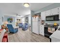 View of open concept living room and kitchen with light wood flooring, light blue walls and white appliances at 1582 S Waccamaw Dr. # 44, Murrells Inlet, SC 29576