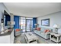 Bright living room with comfortable seating and a sliding glass door to the outside balcony at 201 74Th Ave. N # 2549/2550, Myrtle Beach, SC 29577